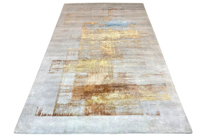 Designer rug with an abstract patchwork pattern in light gray, beige, gold, and blue