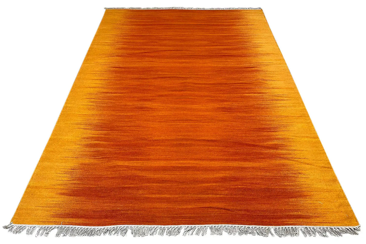 Yellow-orange kilim rug with fringes, viewed from above in a wide rectangle