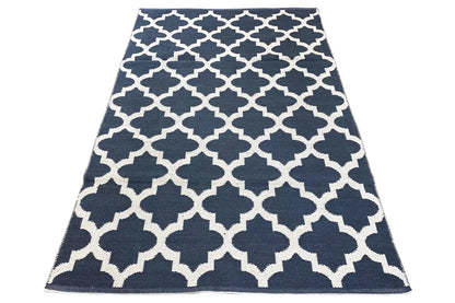 Kilim rug with a dark blue background and white geometric pattern, lying flat