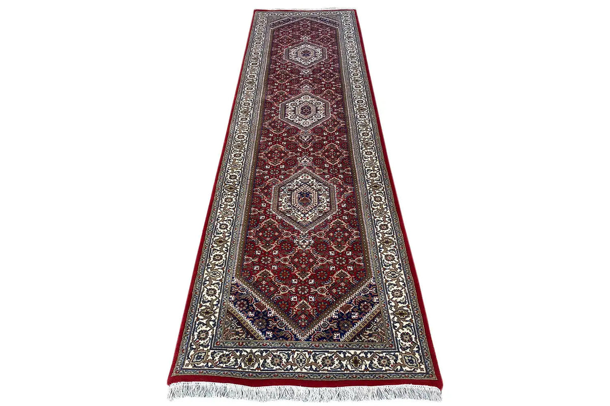 Bidjar runner in burgundy with central diamonds, a decorative border all around, and fringes at the bottom.