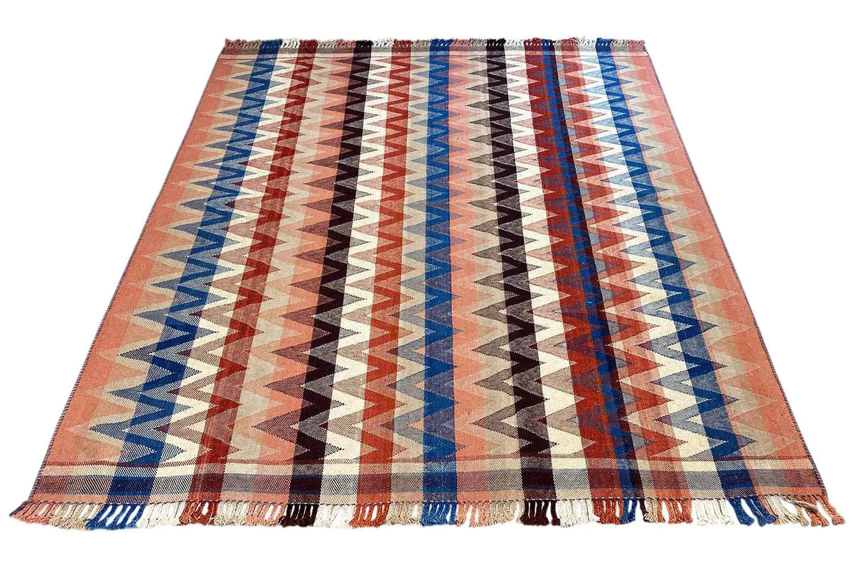 Rectangular rug with a zigzag pattern in rust, blue and white, with fringes