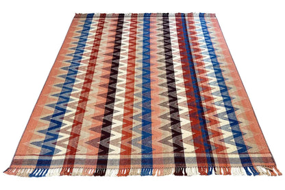 Rectangular rug with a zigzag pattern in rust, blue and white, with fringes