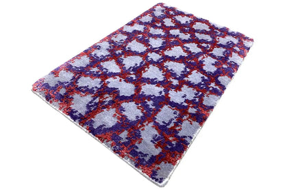 Rectangular rug with an abstract blue-red-purple ornamental pattern on a light background.