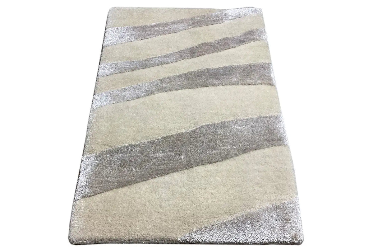 Rectangular rug with a light beige base and gray stripes, viewed from the corner