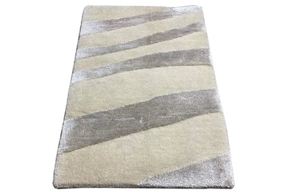 Rectangular rug with a light beige base and gray stripes, viewed from the corner