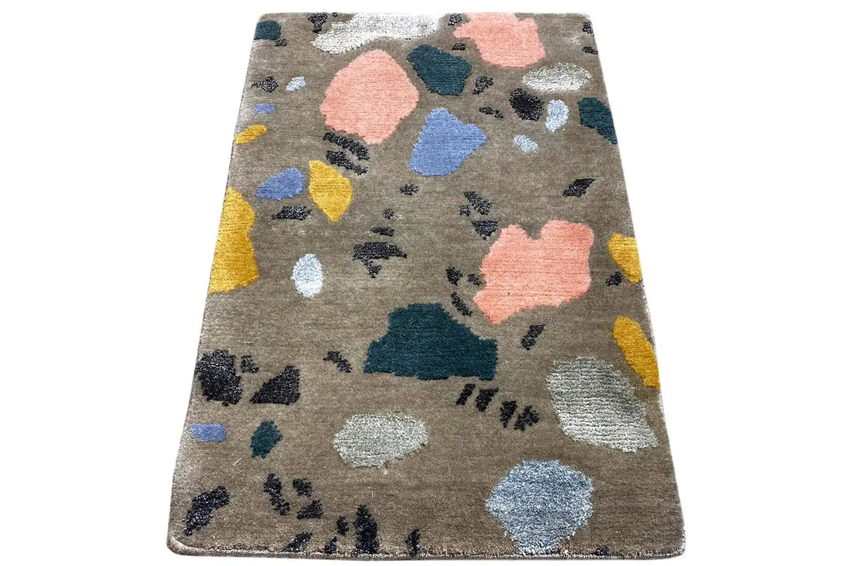 Beige rug with an abstract spotted pattern in blue, pink, yellow, and dark gray