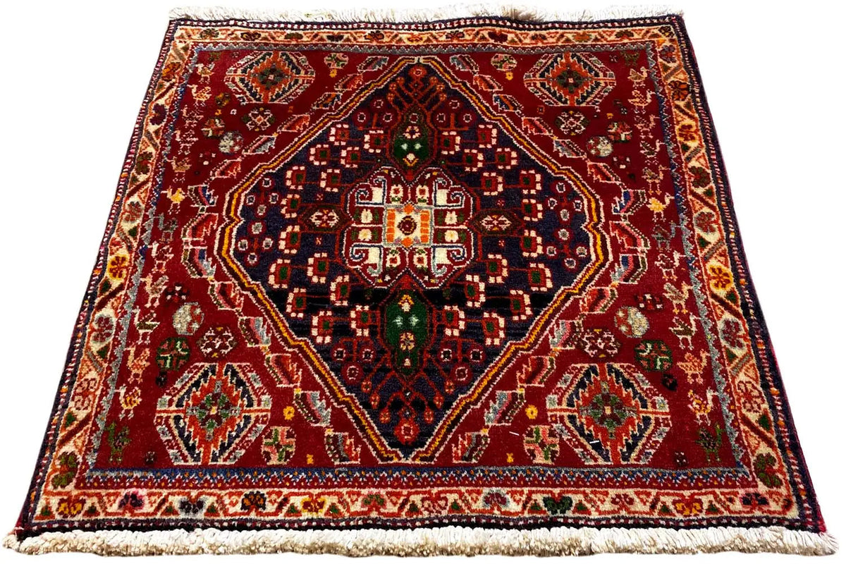 Reddish-brown rug with a symmetrical medallion pattern, border, and fringes