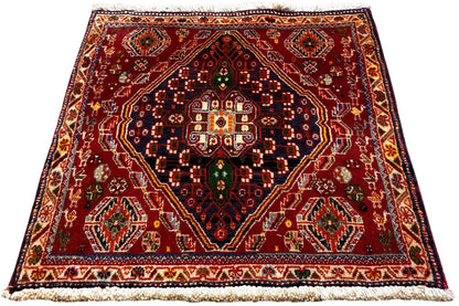 Reddish-brown rug with a symmetrical medallion pattern, border, and fringes