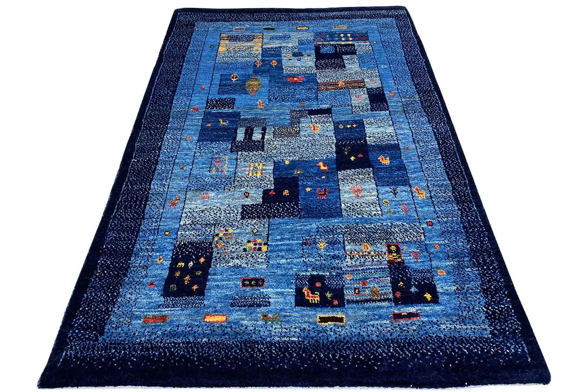 Blue Gabbeh rug with a central patchwork design and dark border