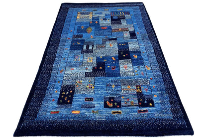 Blue Gabbeh rug with a central patchwork design and dark border