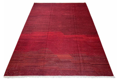 Red kilim rug in a trapezoidal shape with fine fringes and striped color gradients