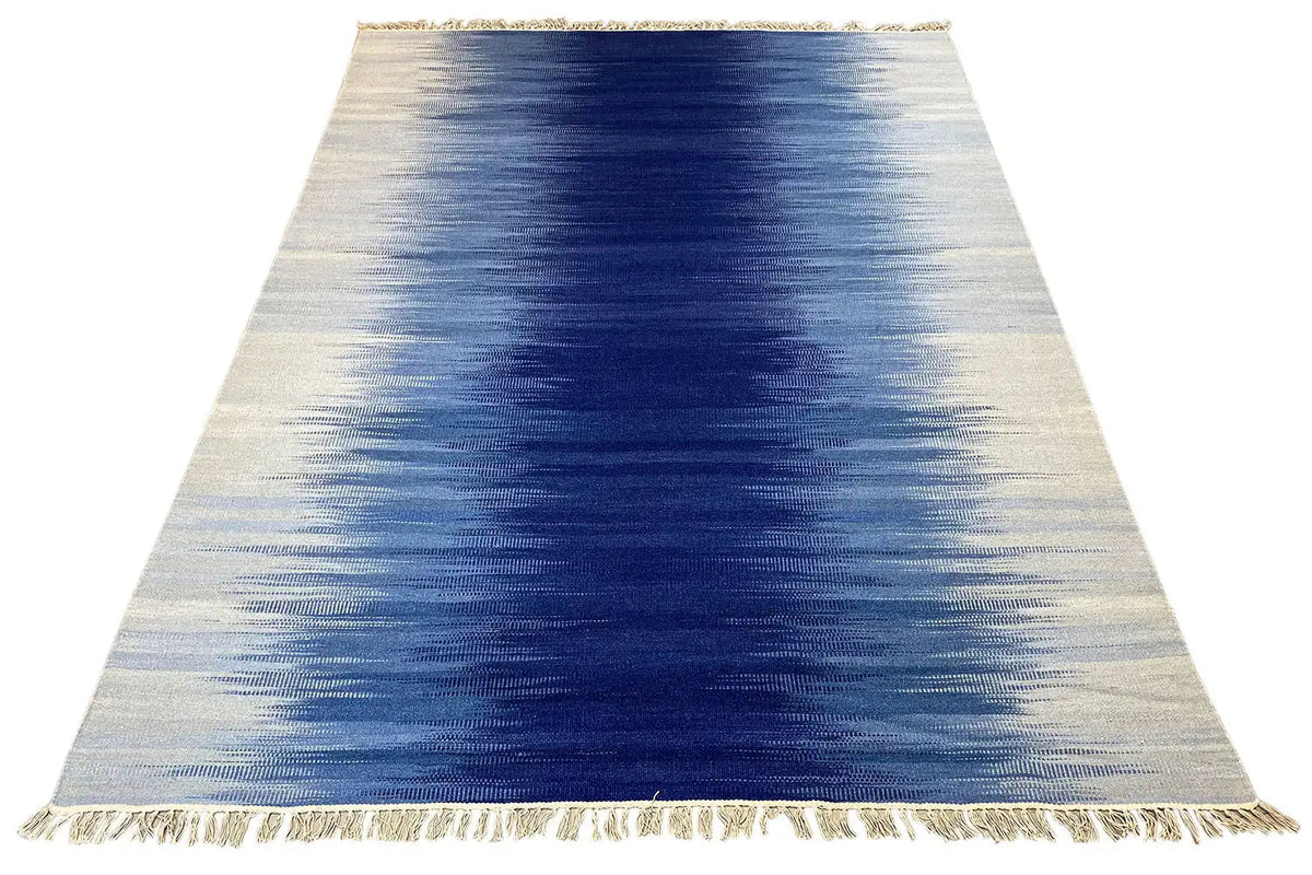 Kilim dhurrie rug with a blue gradient pattern and fringes along the edge