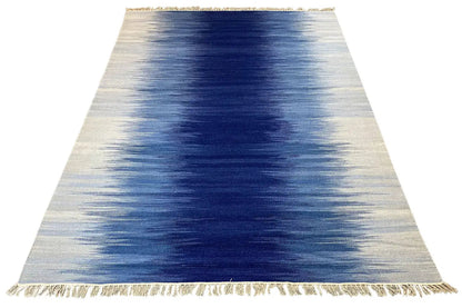 Kilim dhurrie rug with a blue gradient pattern and fringes along the edge