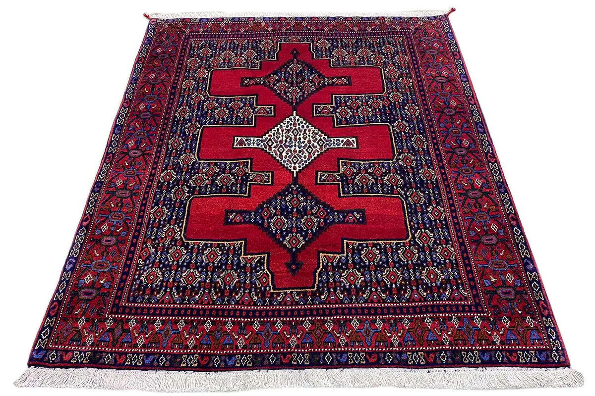 Rug viewed from above: red and dark blue pattern with large star-shaped elements, with fringes.