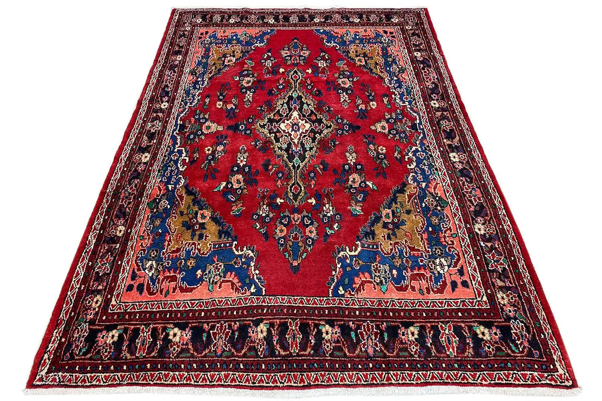Oriental rug spread out, red center with a blue border and colorful ornaments