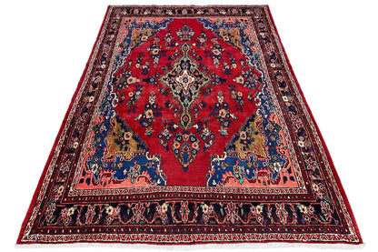 Oriental rug spread out, red center with a blue border and colorful ornaments