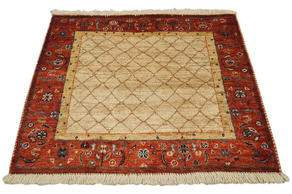 Square rug 62x62 cm with a beige center, red ornamental border, and fringes.