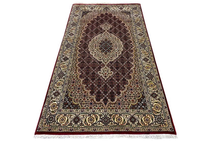 Rug with a central medallion and fringed edge, in dark brown, cream, and gold