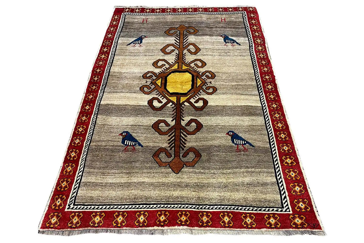 Gabbeh rug in trapezoidal view: beige ground, red border trim, birds, and ornamental medallion