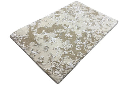 Designer rug with a beige pile and white abstract pattern, diagonal view