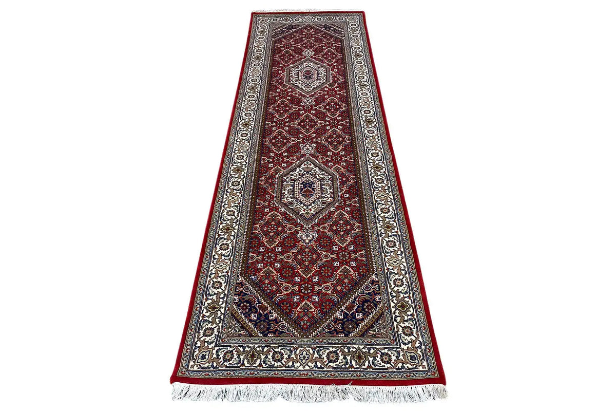 Bidjar runner with a red medallion motif, dark border, and fringe along the bottom edge.