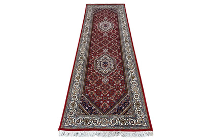 Bidjar runner with a red medallion motif, dark border, and fringe along the bottom edge.
