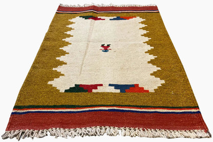 Rectangular ochre kilim rug with a white field, figure border, and red fringes