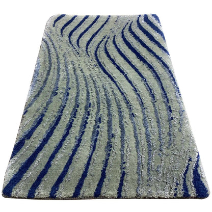 Designer rug with a light gray base and dark blue wavy stripes, slightly angled