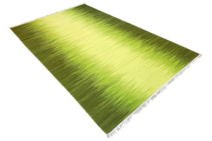 Green kilim rug at an angle with white fringed edging