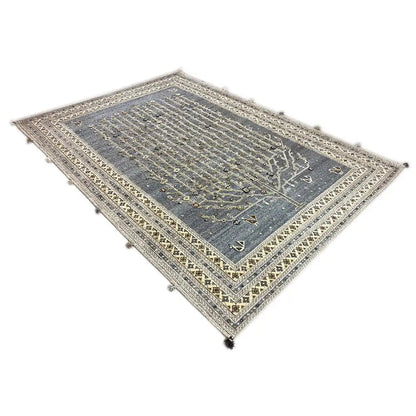 Rug with a blue-gray center and gold-colored border pattern, corners with tassels