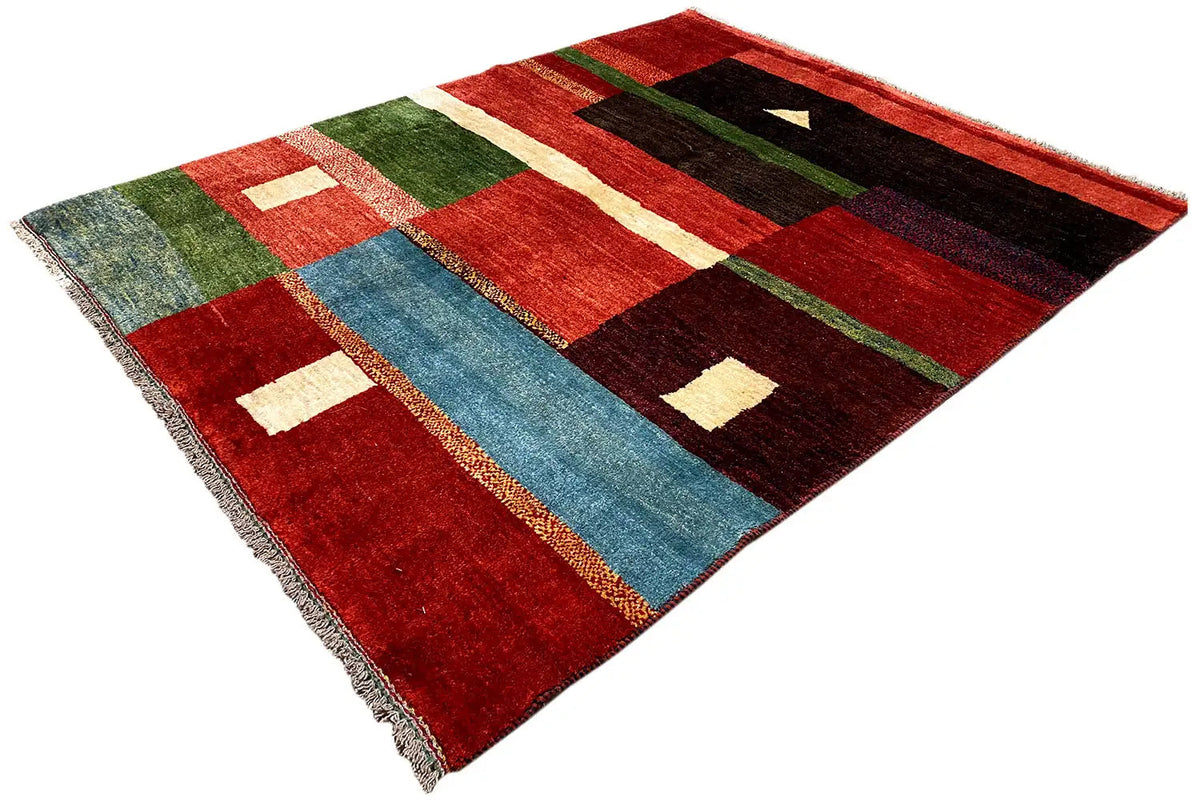 Gabbeh rug at an angle: red and green areas with white accents and blue stripes