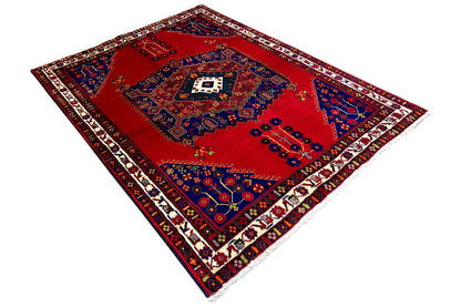 Rug in angled view: red center with a blue pattern, multicolored border