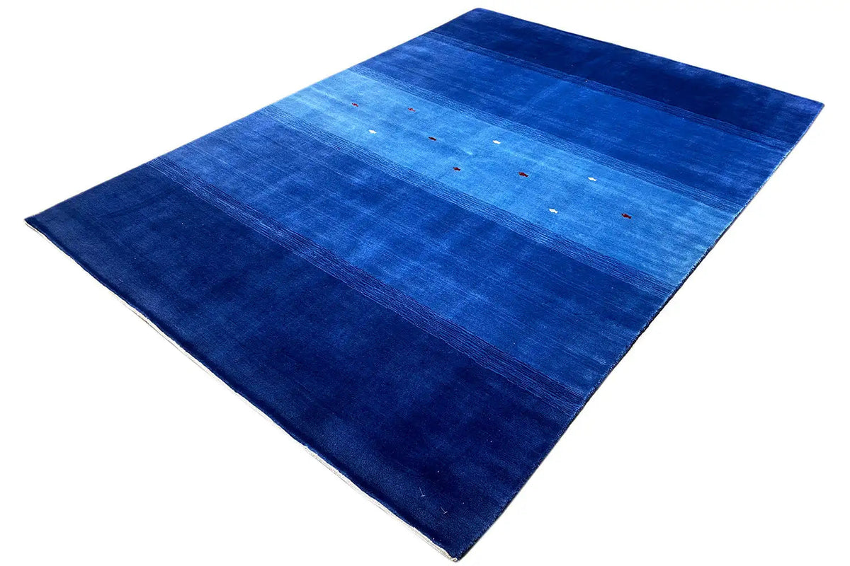 Blue Gabbeh rug, diagonal view: bands of color with small red and white dots