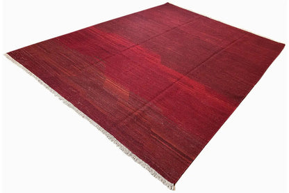 Red kilim rug, diagonal view, with white fringes and a geometric grid pattern