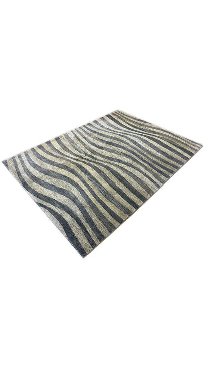 Gabbeh rug draped at an angle: zebra stripes in blue, gray, and beige