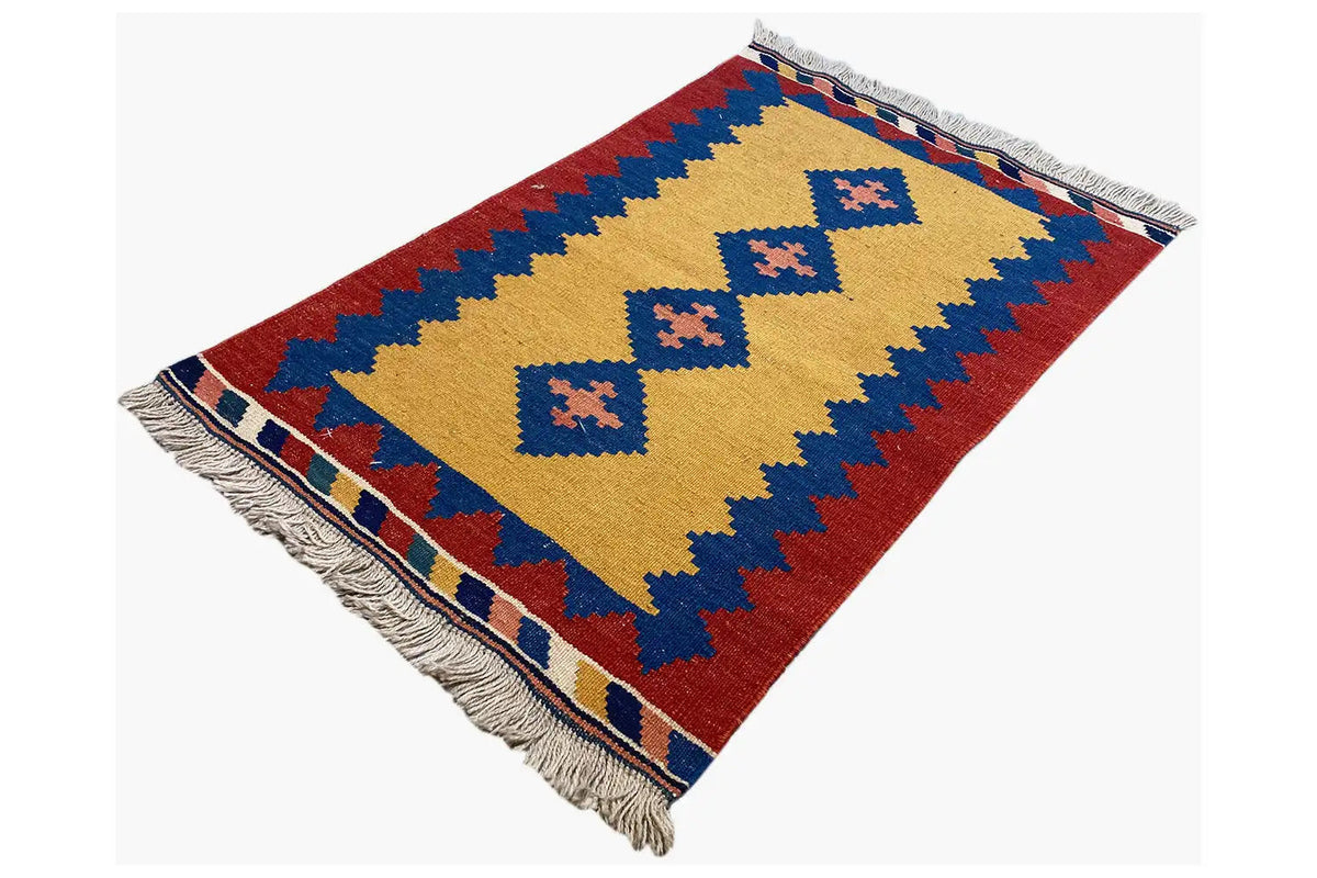 Kilim rug, laid at an angle: yellow pattern on red with blue zigzag borders; fringes