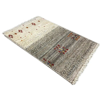 Gabbeh rug laid flat: beige-gray areas with colorful medallion motifs and fringes