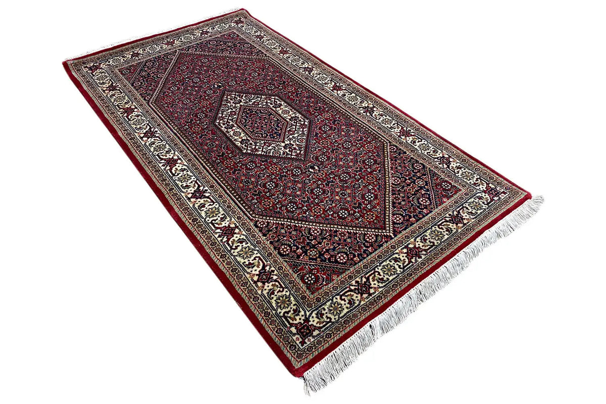 Rug with a burgundy pattern, wide border, and fringe along the bottom edge.