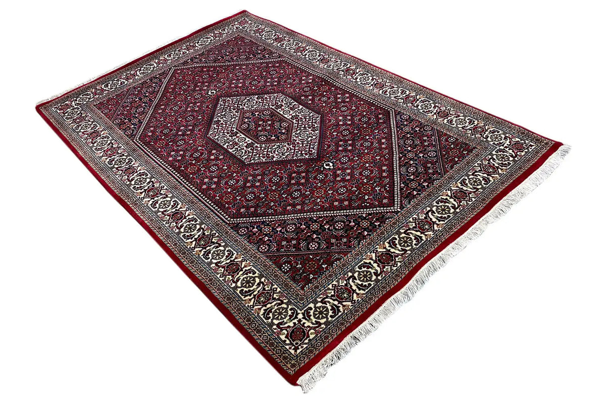 Corner view: burgundy medallion ornament with a gray-brown border and fringe