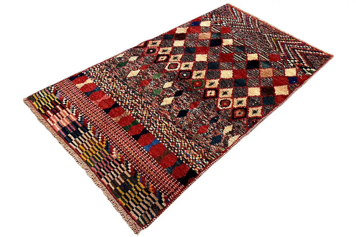 Rug with checkerboard and diamond patterns in shades of red, blue, and beige