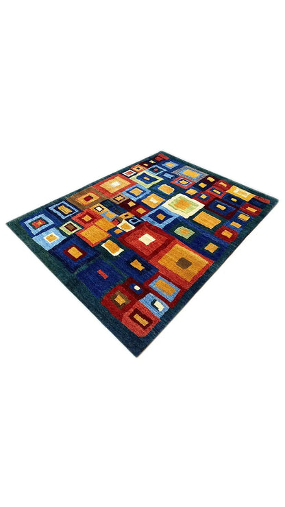 Gabbeh rug at an oblique angle, geometric squares in blue, red, yellow, and white.