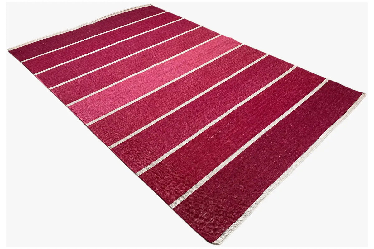Red kilim rug with light stripes, diagonal view with visible edge