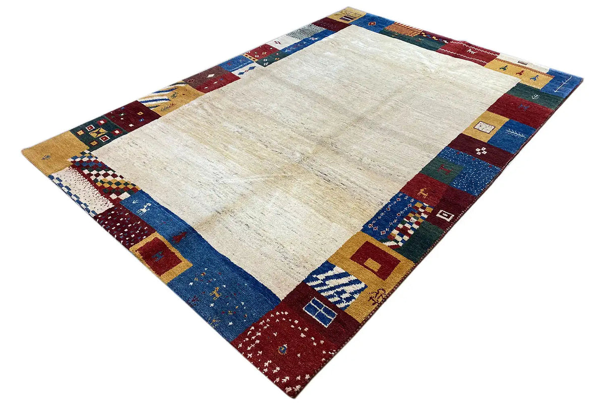 Gabbeh rug, diagonal: light center with a colorful patchwork border in blue, red, and yellow