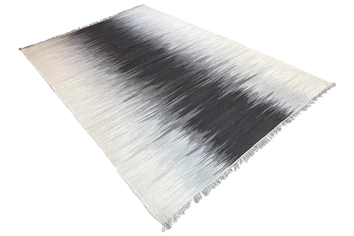 Kelim rug in light gray with a dark zoned look, diagonal view and fringes