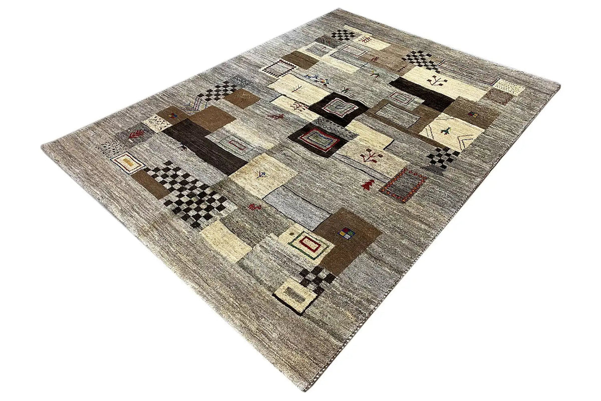 Gabbeh rug shown at an angle: geometric blocks and patches of color in gray, beige, and brown