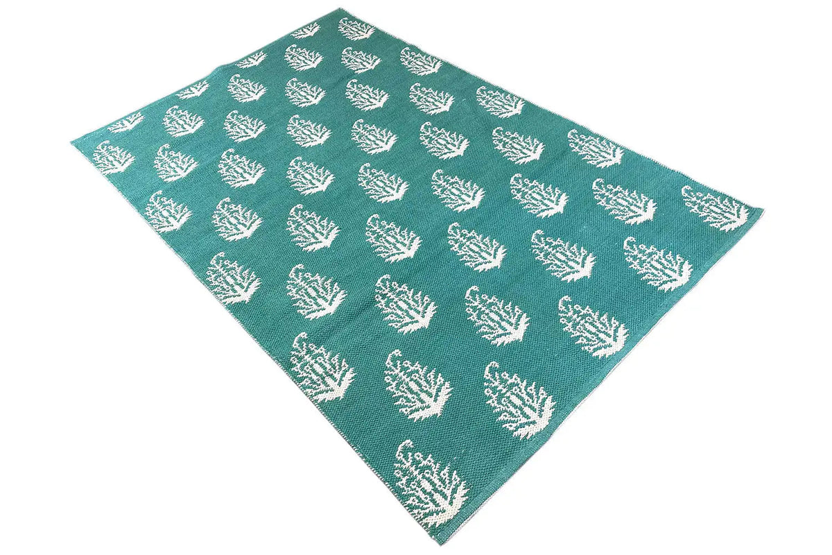 Modern green kilim rug with a white tree pattern, draped diagonally