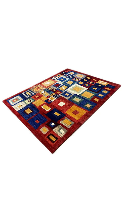 Gabbeh rug stretched out with geometric squares in shades of blue, red, and yellow