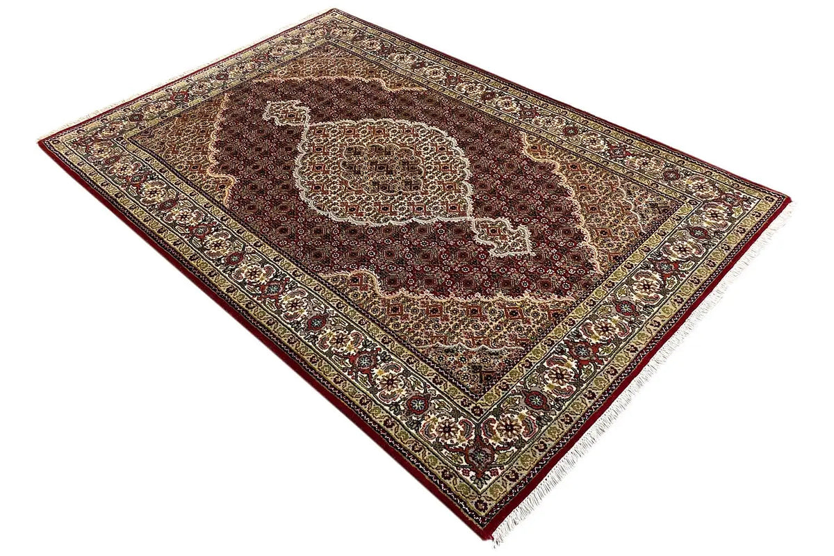 Indo Tabriz rug, diagonal view with a red field and golden ornamental border