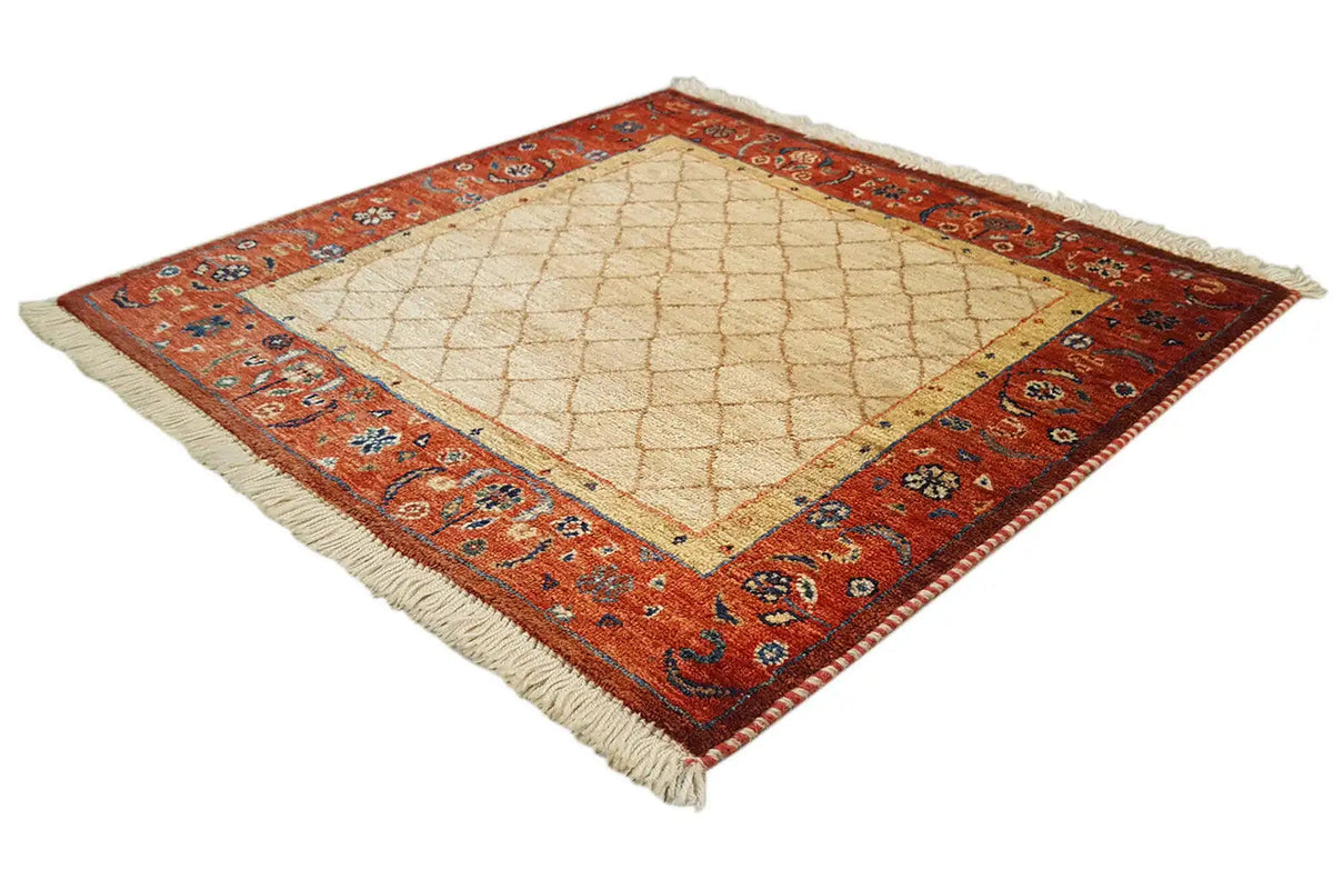 Square rug laid out, beige center with a red patterned border, visible fringes.