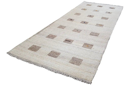 Kelim runner laid crosswise: beige background with brown square motifs, fringes along the edges
